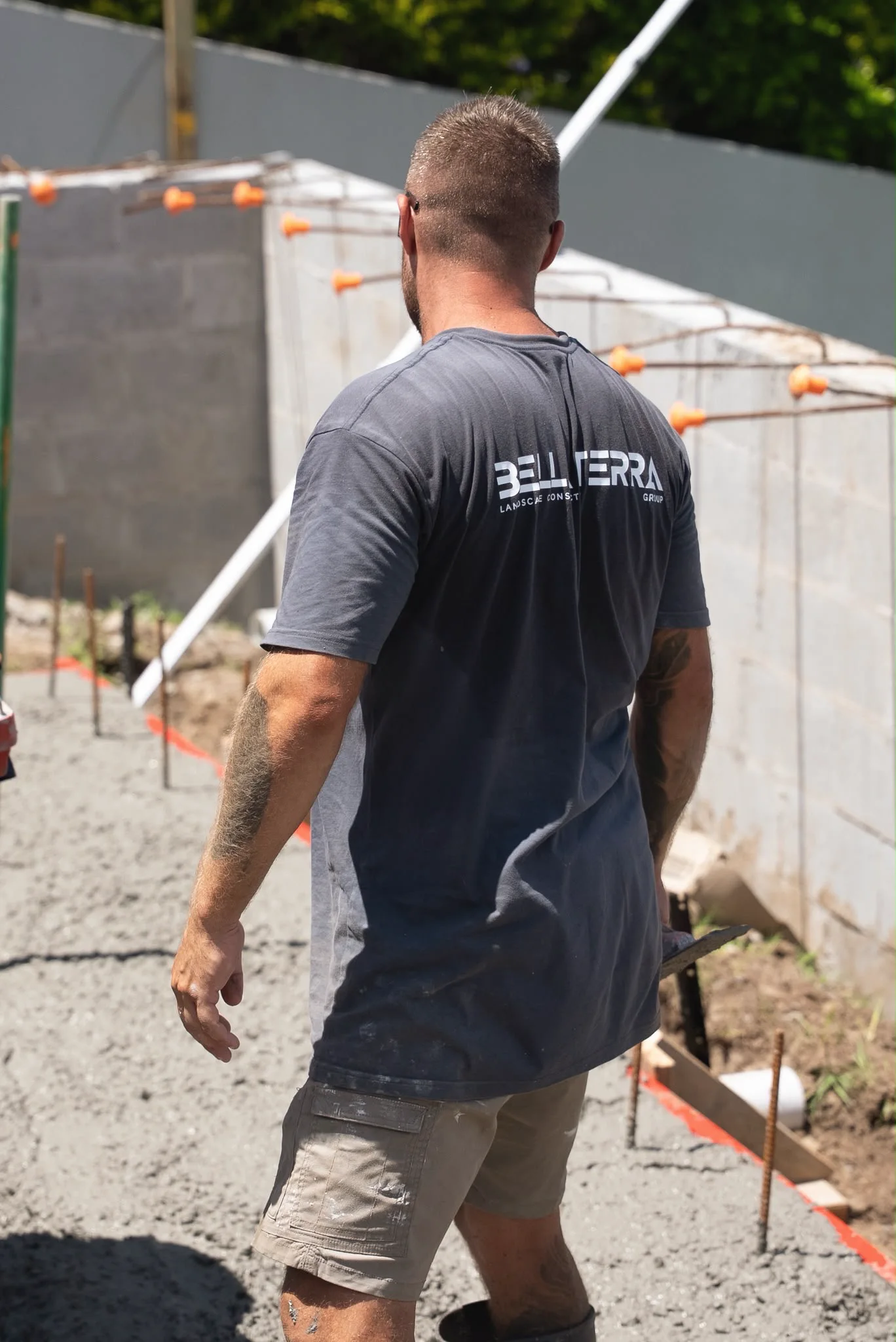 A crew member in a Bella Terra shirt on a fresh slab pour beside a block wall