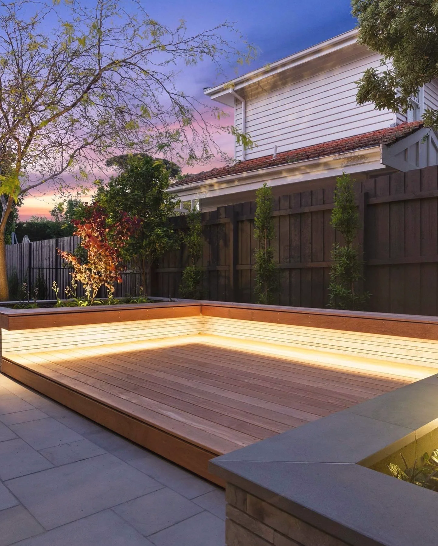 Corner of a hardwood deck lit by an LED strip under its edge, at dusk