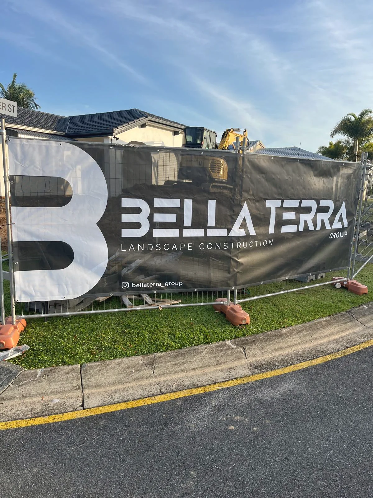 Bella Terra Group banner on the site fence, an excavator working behind it