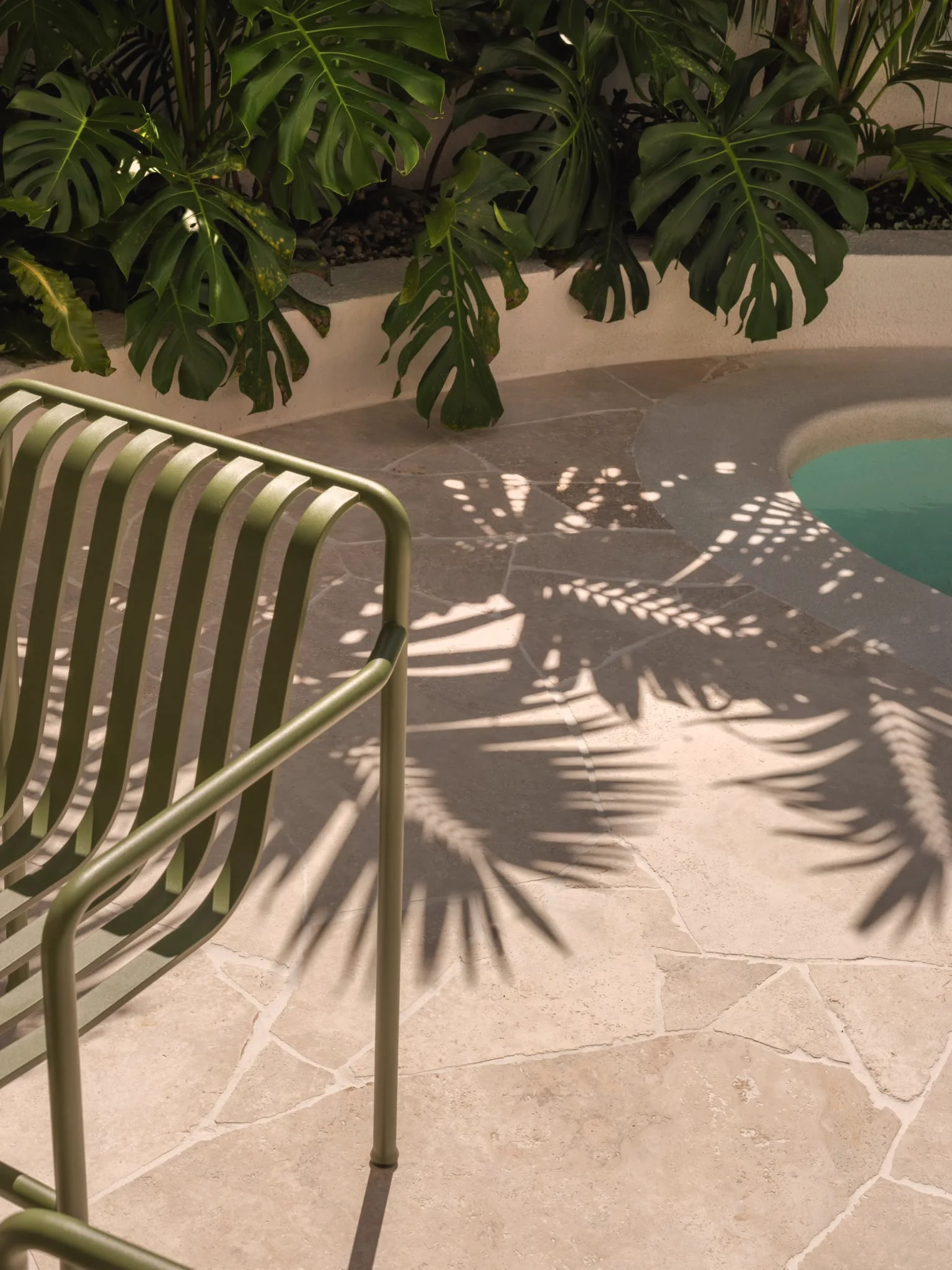 Palm shadows across sandstone crazy paving beside a plunge pool