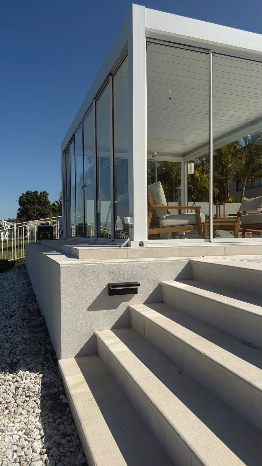 Pale limestone steps and terrace with a step light, rising to a glass garden room