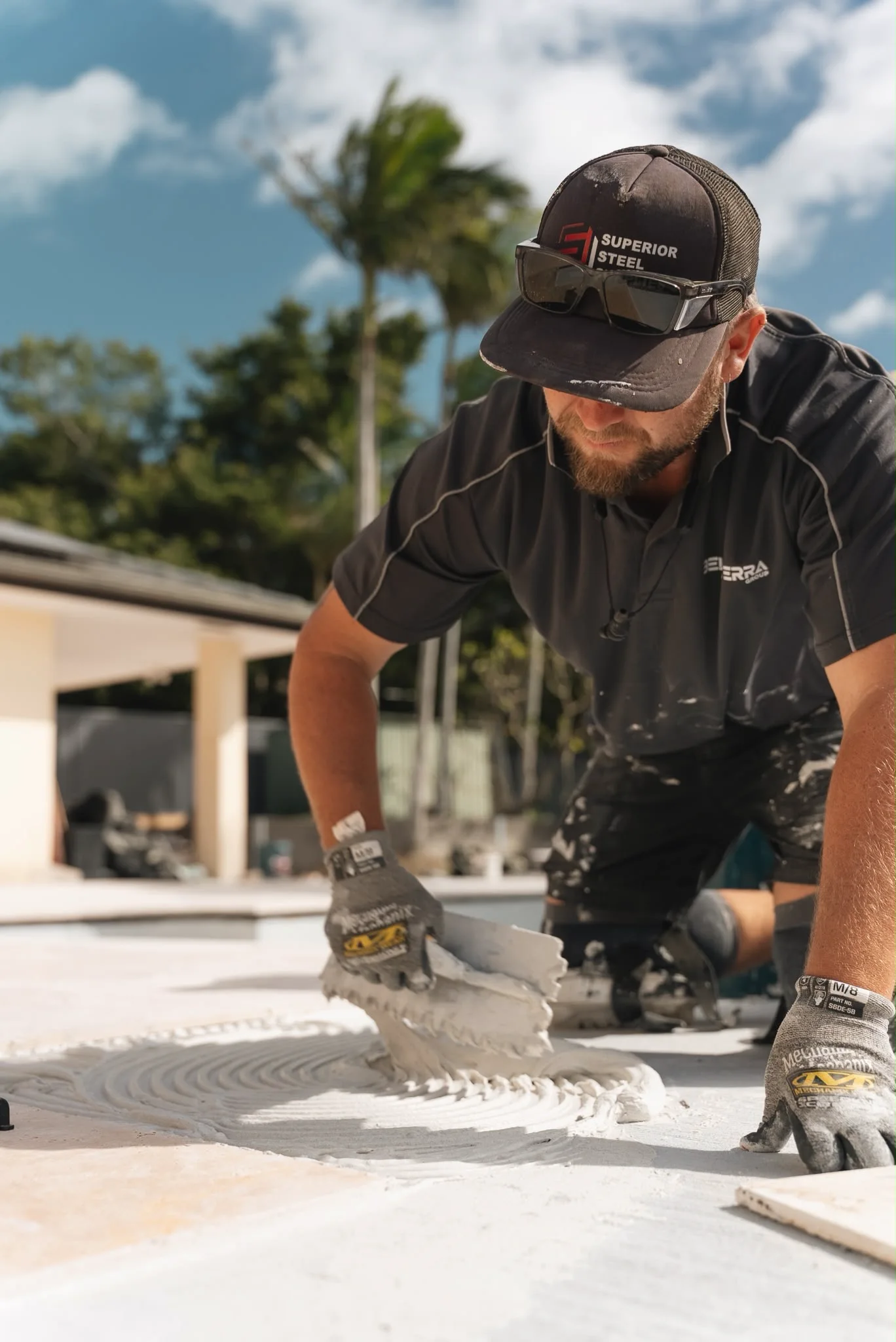 A Bella Terra crew member combing adhesive with a notched trowel before a paver goes down