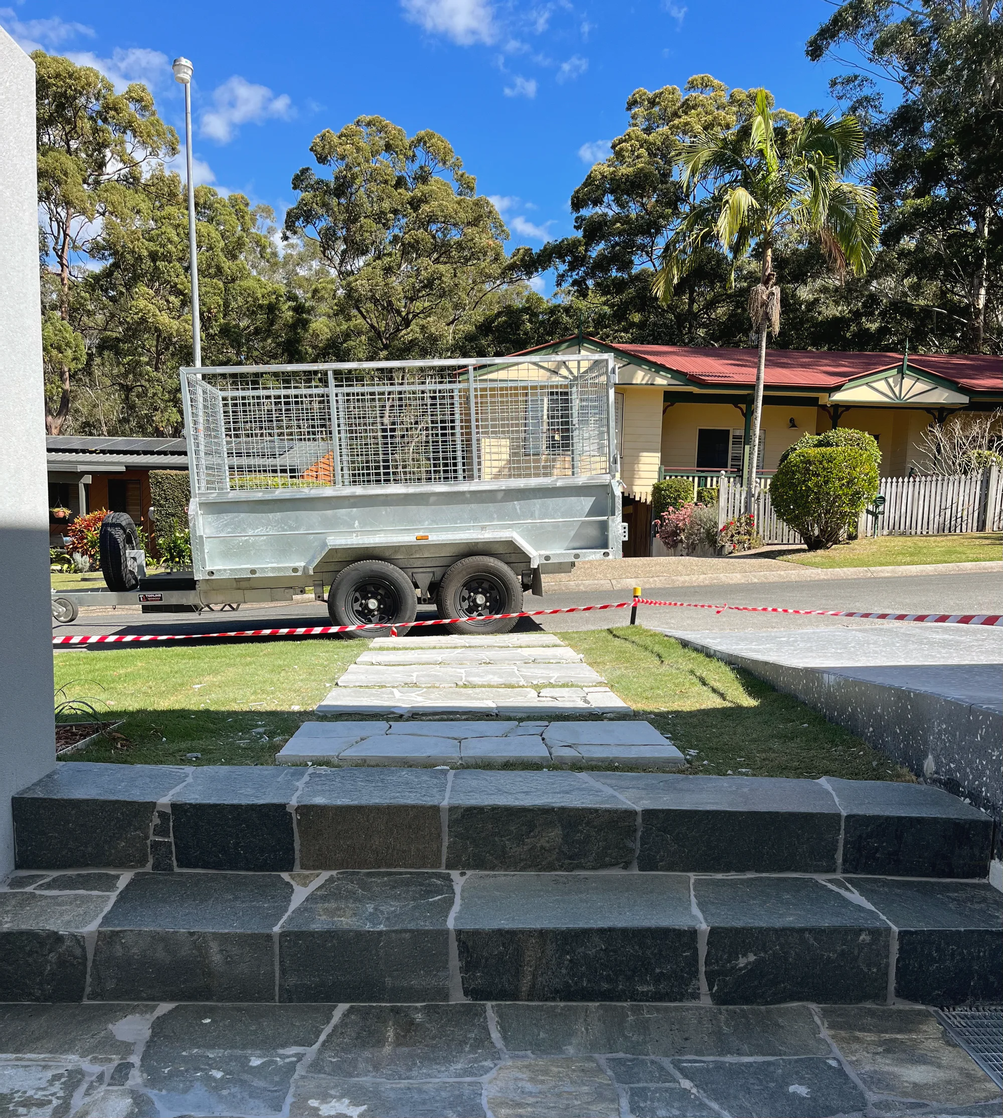 New dark stone steps and stepping stones to the street, with the work trailer parked beyond